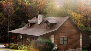 A log cabin with a stone chimney, a porch with a railing, and a sign indicating it is a country inn. - Er31 - Grandma And Granpaws Place - Great Location - Close To Parkway In Pf 2 Bedroom Cabin by RedAwning (Pigeon Forge)