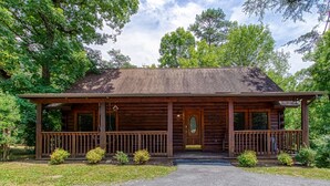 A wooden cabin with a porch, a front door, and a small front yard. - Er75 - Palmetto Place - Great Location! Close To All The Action! 2 Bedroom Cabin by RedAwning (Pigeon Forge)