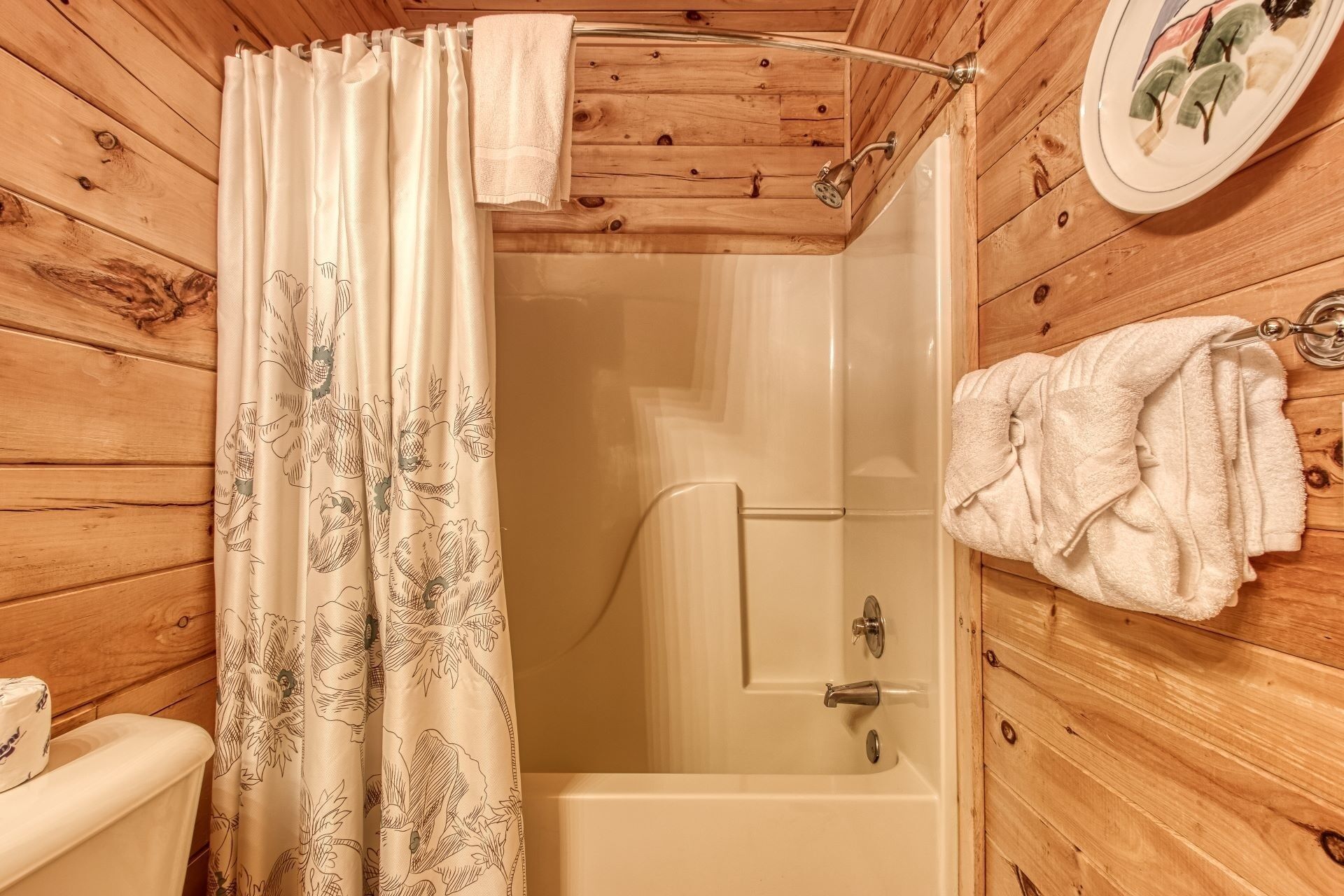 Ein Badezimmer mit Holzwänden, einer Dusche, einer Toilette und einem Handtuchhalter.