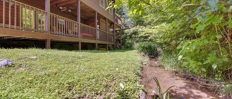 A wooden building with a covered porch and a small stream running alongside.