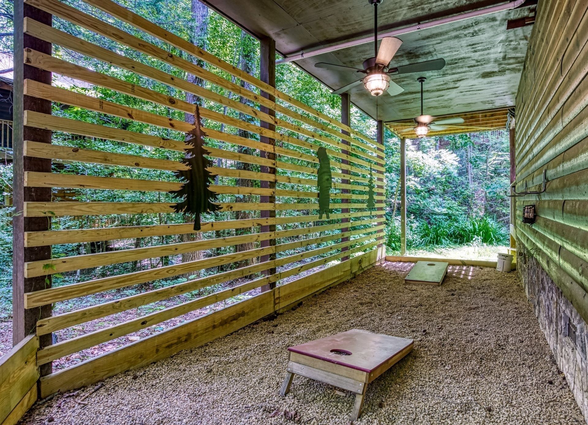 A rustic wooden interior with a slatted wall, a ceiling fan, and a small wooden table.