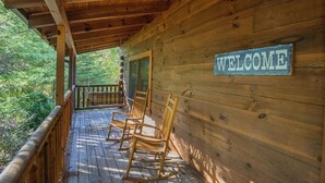 A wooden cabin with a porch, rocking chairs, and a 'WELCOME' sign. - ER244 - Black Hawk Hideaway Great Location - Close To Town! 2 Bedroom Cabin by RedAwning (Pigeon Forge)