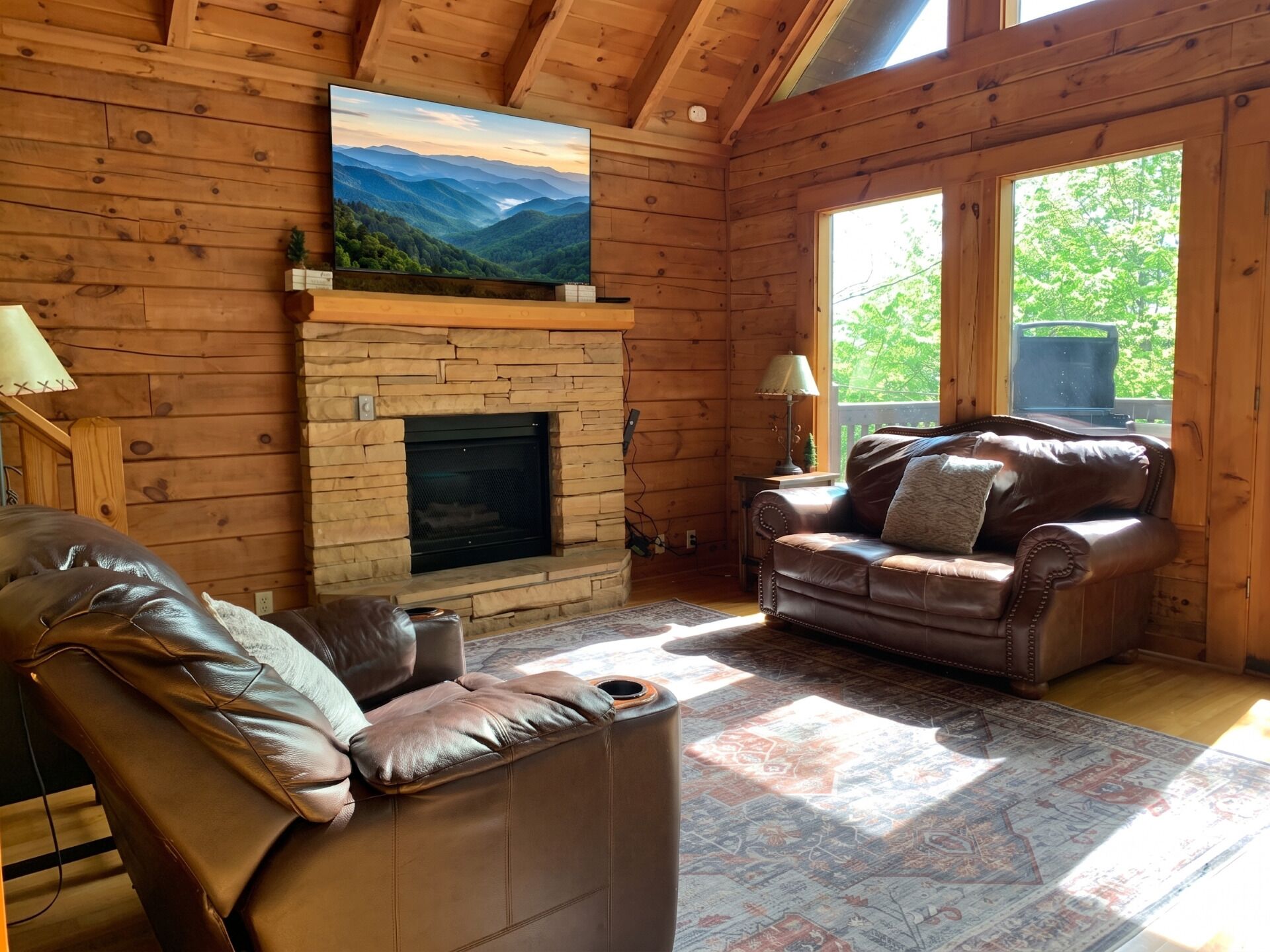 A cozy cabin interior with a fireplace, leather furniture, and a large window.