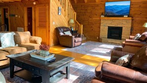 A wooden interior with a fireplace, leather sofas, a coffee table, and a TV mounted on the wall. - Er1 - Smoky Mountain Escape Great Location - Close To Town! 3 Bedroom Cabin by RedAwning (Pigeon Forge)