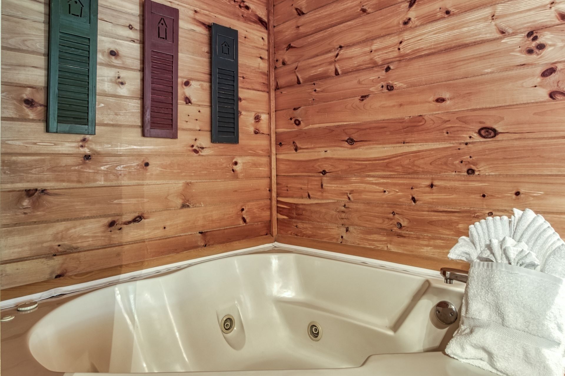 L’intérieur d’un chalet en bois, avec une baignoire, des murs en bois et des volets.