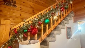 A wooden staircase with a garland of Christmas decorations. - Er27- Bear Naked - Great Location- Close To Town 2 Bedroom Cabin by RedAwning (Pigeon Forge)