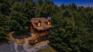 A wooden cabin with a balcony, surrounded by dense forest. - Er27- Bear Naked - Great Location- Close To Town 2 Bedroom Cabin by RedAwning (Pigeon Forge)