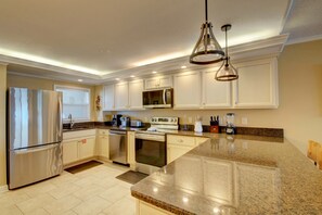 A modern kitchen with white cabinets, stainless steel appliances, granite countertops, and pendant lighting. - 466 El Matador 2 Bedroom Condo by RedAwning (Fort Walton Beach)