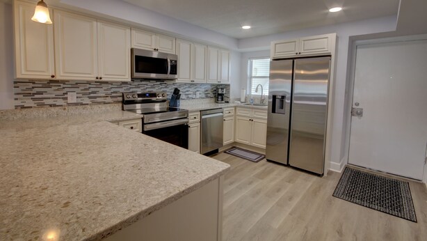 A modern kitchen with white cabinets, stainless steel appliances, and a granite countertop. - 461 El Matador 2 Bedroom Condo by RedAwning (Fort Walton Beach)