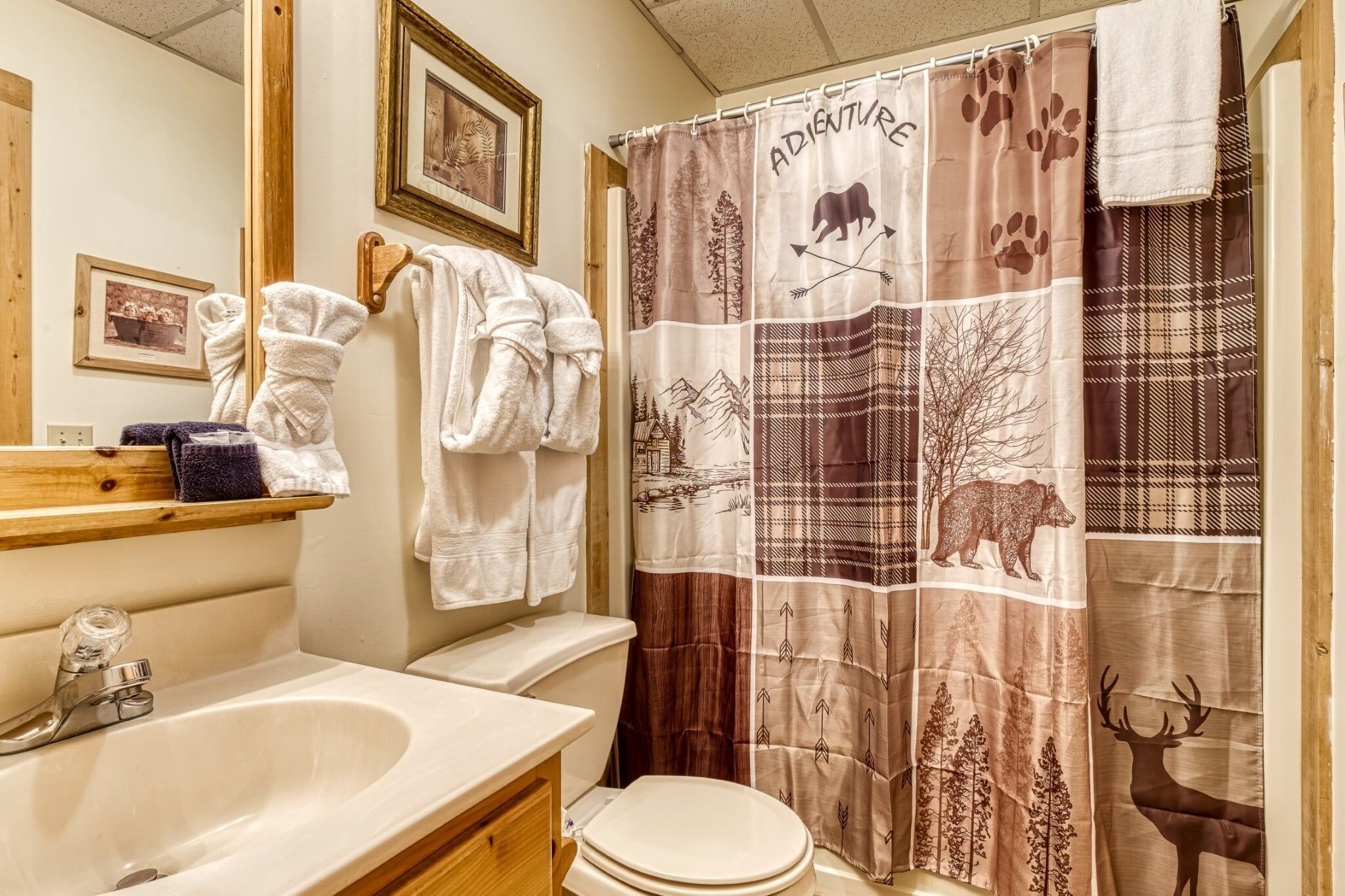 Een badkamer met een wastafel, toilet en douchegordijn met dierenprints.