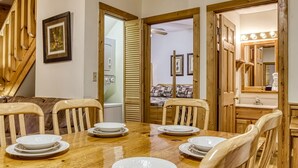 A wooden dining table with chairs, a staircase, and a mirror with lights. - Er202 - Now And Forever Great Location! - Close To Town! 4 Bedroom Cabin by RedAwning (Pigeon Forge)