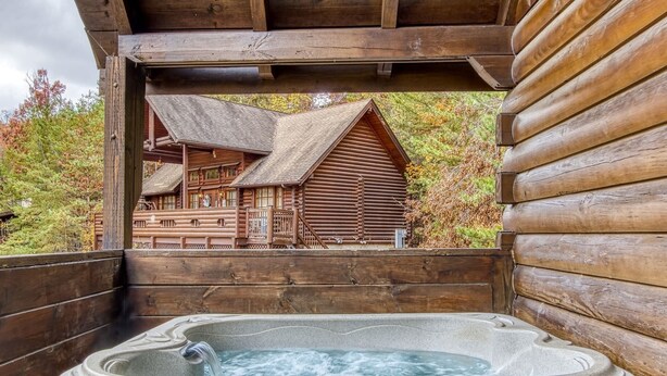 A wooden cabin with a hot tub and a view of another cabin. - Er13 - Moose Manor Great Location - Close To Town! 3 Bedroom Cabin by RedAwning (Pigeon Forge)