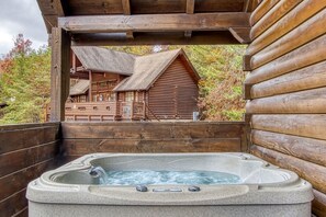 A wooden cabin with a hot tub and a view of another cabin. - Er13 - Moose Manor Great Location - Close To Town! 3 Bedroom Cabin by RedAwning (Pigeon Forge)