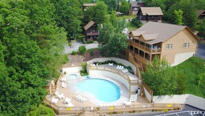 An aerial view of a resort with a large pool, multiple decks, and surrounding greenery. - Er13 - Moose Manor Great Location - Close To Town! 3 Bedroom Cabin by RedAwning (Pigeon Forge)