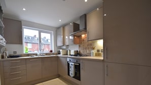 A modern kitchen with beige cabinets, a built-in oven, and a window providing natural light. - Southbank (Rye)