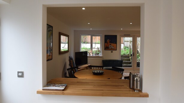 A modern living room with a wooden dining table, a television, and artwork on the walls. - Southbank (Rye)
