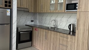 Una cocina moderna con armarios de madera, un refrigerador Bosch, un horno de acero inoxidable, un microondas y un lavamanos.