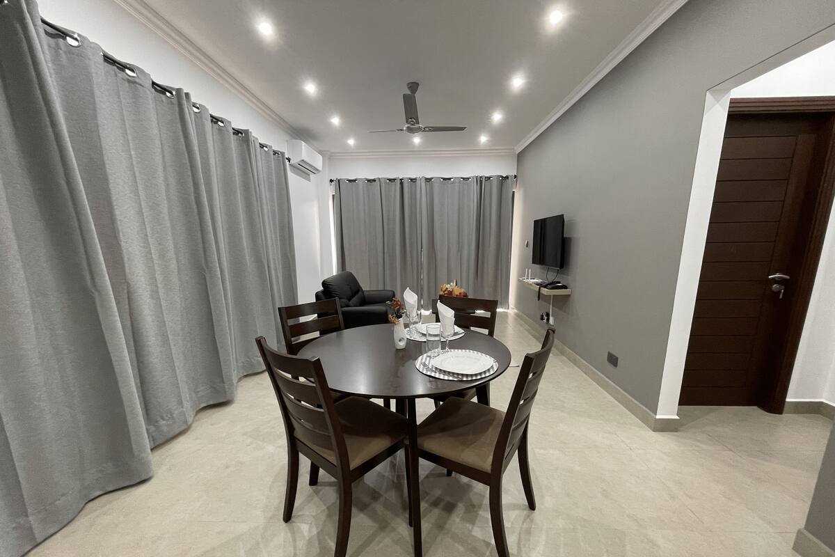 A dining area with a round table, chairs, and a ceiling fan.