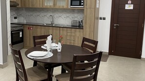 Una cocina moderna con gabinetes de madera, un microondas y una estufa. Hay una mesa de comedor con sillas y un pequeño jarrón con flores.