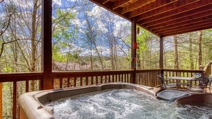 Un jacuzzi en una terraza de madera con vistas a un bosque.