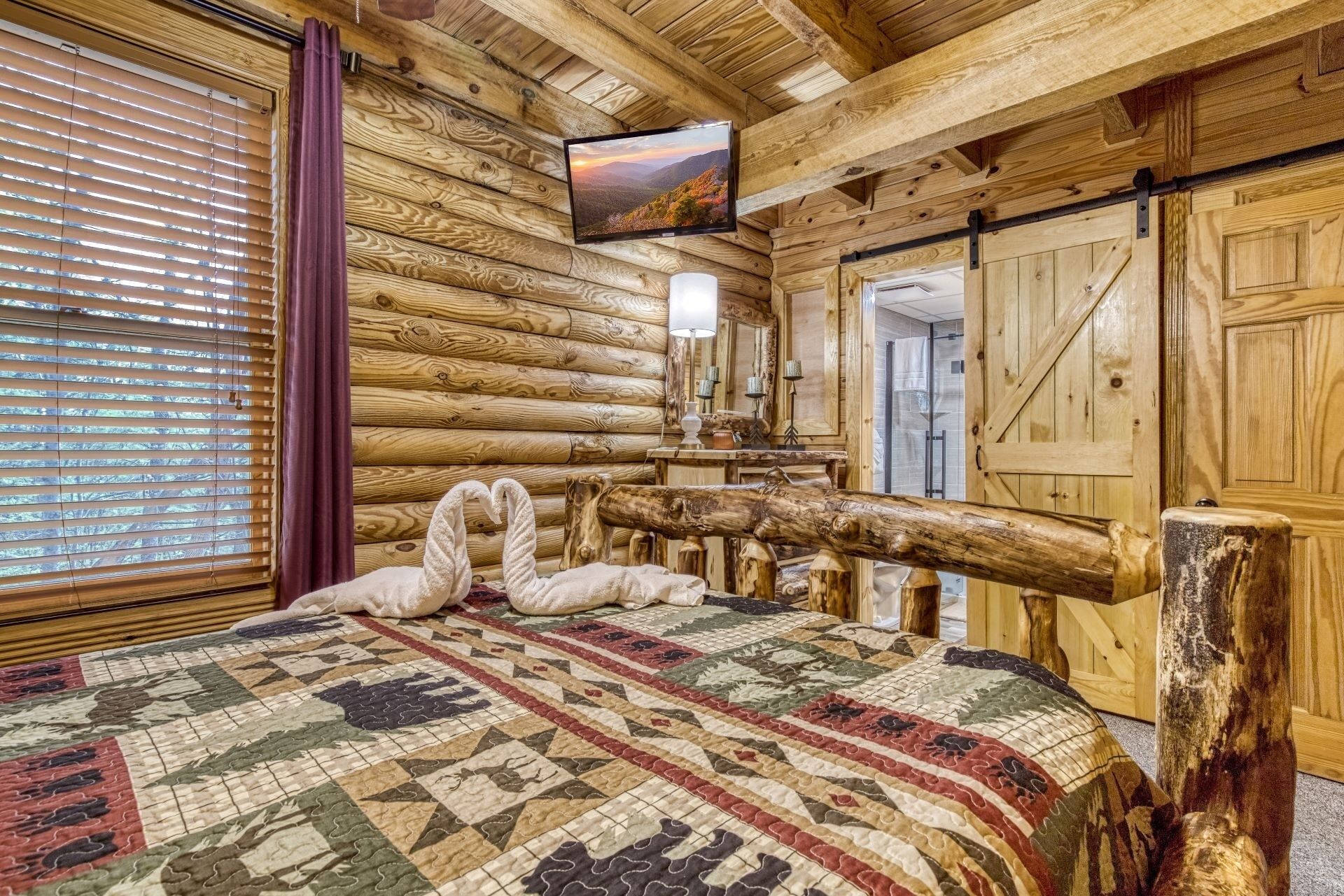 Una habitación tipo cabaña de madera con cama, paredes de madera, televisor y decoración rústica.