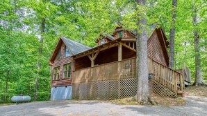 A wooden cabin with a balcony, surrounded by trees. - Whispering Oaks - Private Pigeon Forge Getaway...close To Tanger Outlet Shopping 2 Bedroom Cabin by RedAwning (Sevierville)