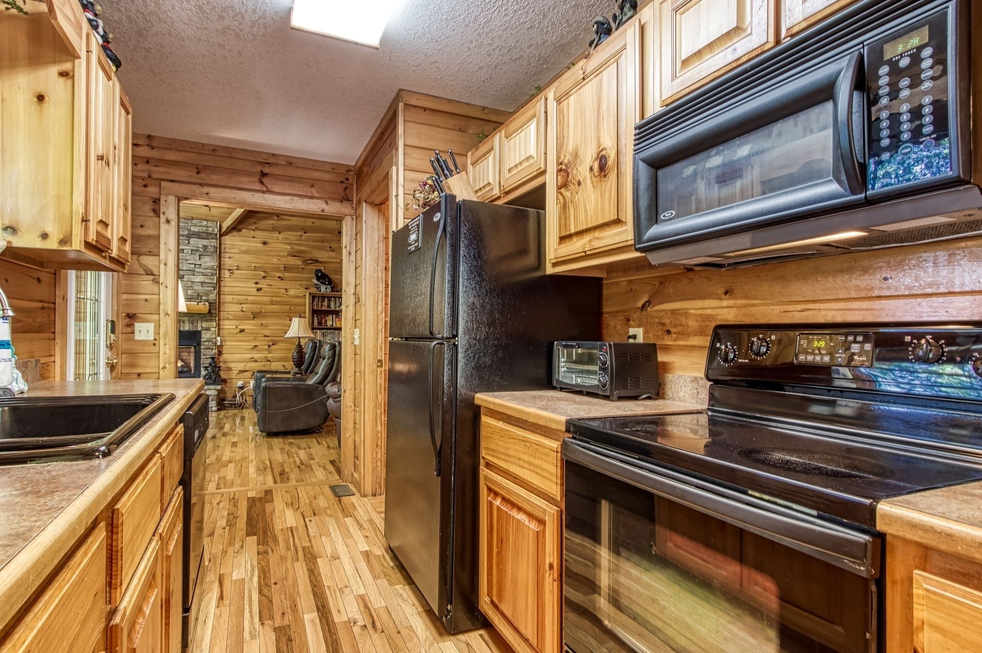 A kitchen with wooden cabinets, a refrigerator, a microwave, a toaster, and an oven.