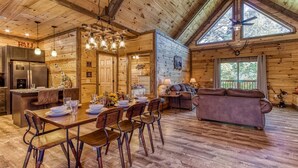 Une vaste cabane en rondins comprenant un coin repas, une cuisine et un salon.