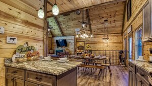 L’intérieur d’un chalet rustique, avec un revêtement mural en bois, un coin repas et une cuisine.