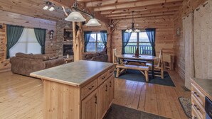 A wooden cabin interior with a kitchen, dining area, and living room. - Bear Hugs - Great Cabin! 2 Bedroom Cabin by RedAwning (Sevierville)