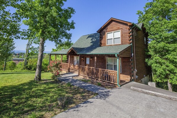 A log cabin with a porch, a covered deck, and a view of the surrounding greenery. - Bear Hugs - Great Cabin! 2 Bedroom Cabin by RedAwning (Sevierville)