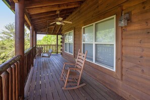 A wooden porch with a ceiling fan, rocking chairs, and a view of trees. - Bear Hugs - Great Cabin! 2 Bedroom Cabin by RedAwning (Sevierville)