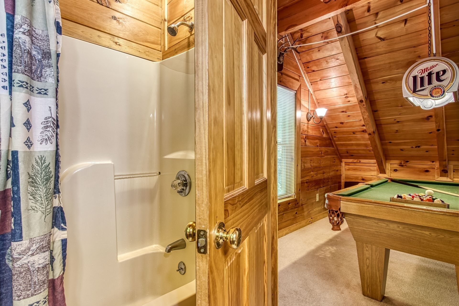 Ein Holzinterieur mit Billardtisch, Dusche und einem Miller Lite-Schild.