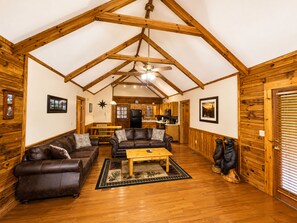 A spacious living room with a high ceiling, wooden beams, a ceiling fan, and a fireplace. - Er79 - Robyn's Nest - Great Location. Close To All The Action! 2 Bedroom Cabin by RedAwning (Pigeon Forge)