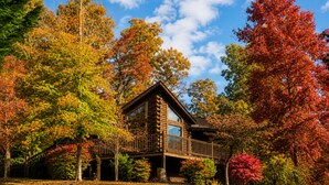 A cabin with a deck, surrounded by autumn foliage. - Er79 - Robyn's Nest - Great Location. Close To All The Action! 2 Bedroom Cabin by RedAwning (Pigeon Forge)