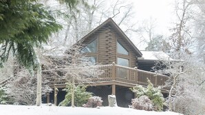A log cabin with a balcony, surrounded by snow-covered trees. - Er79 - Robyn's Nest - Great Location. Close To All The Action! 2 Bedroom Cabin by RedAwning (Pigeon Forge)
