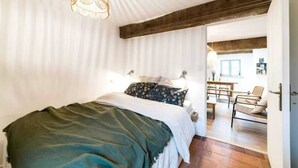 Une chambre à coucher avec un lit, un luminaire suspendu et une poutre en bois au plafond.