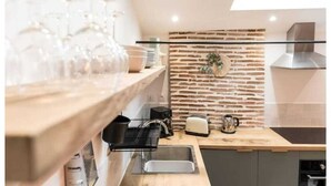 Une cuisine moderne dotée d’un plan de travail en bois, d’un évier encastré, d’un grille-pain et d’une machine à café.