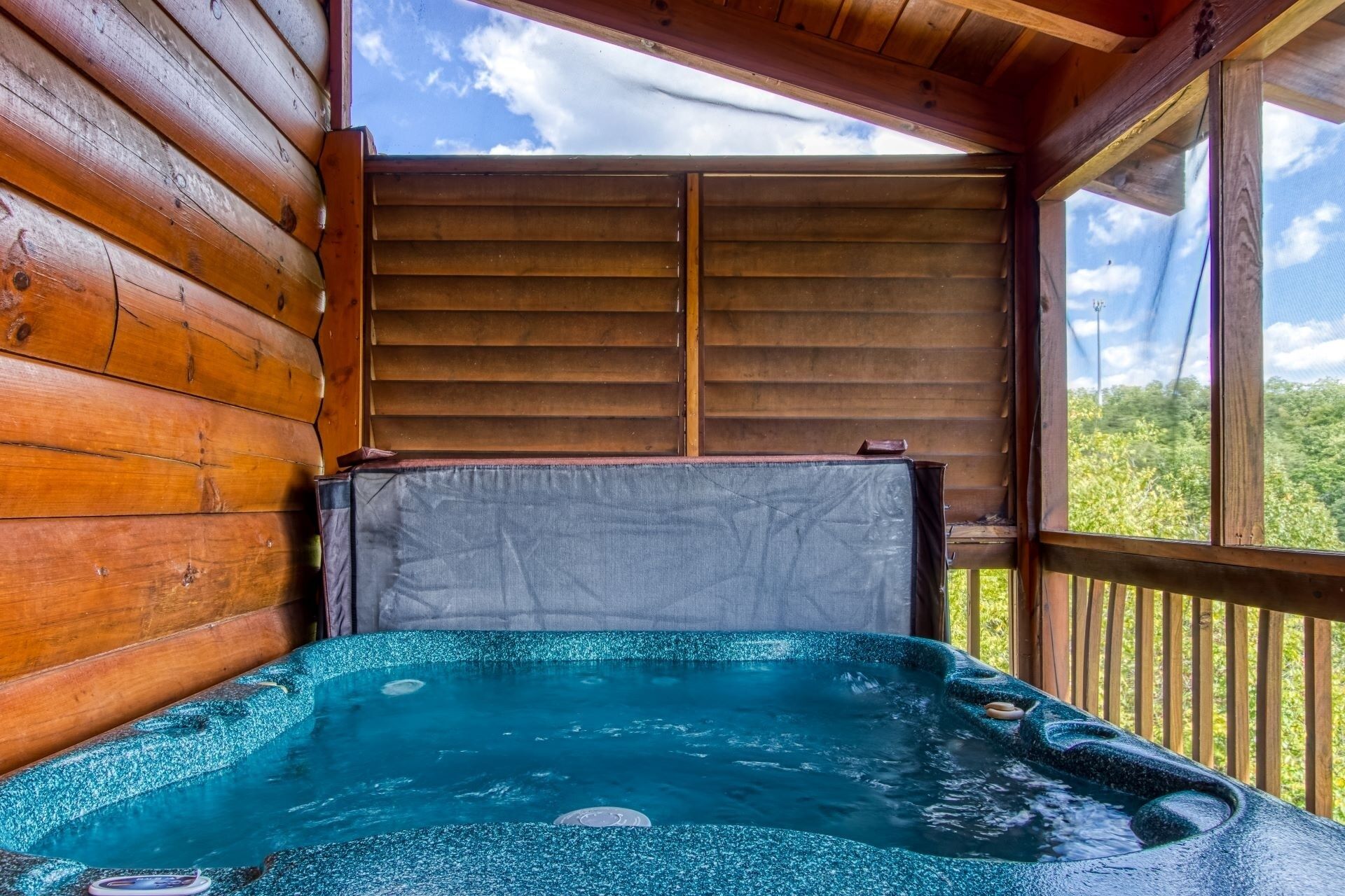 A hot tub with a view of the sky and greenery outside.
