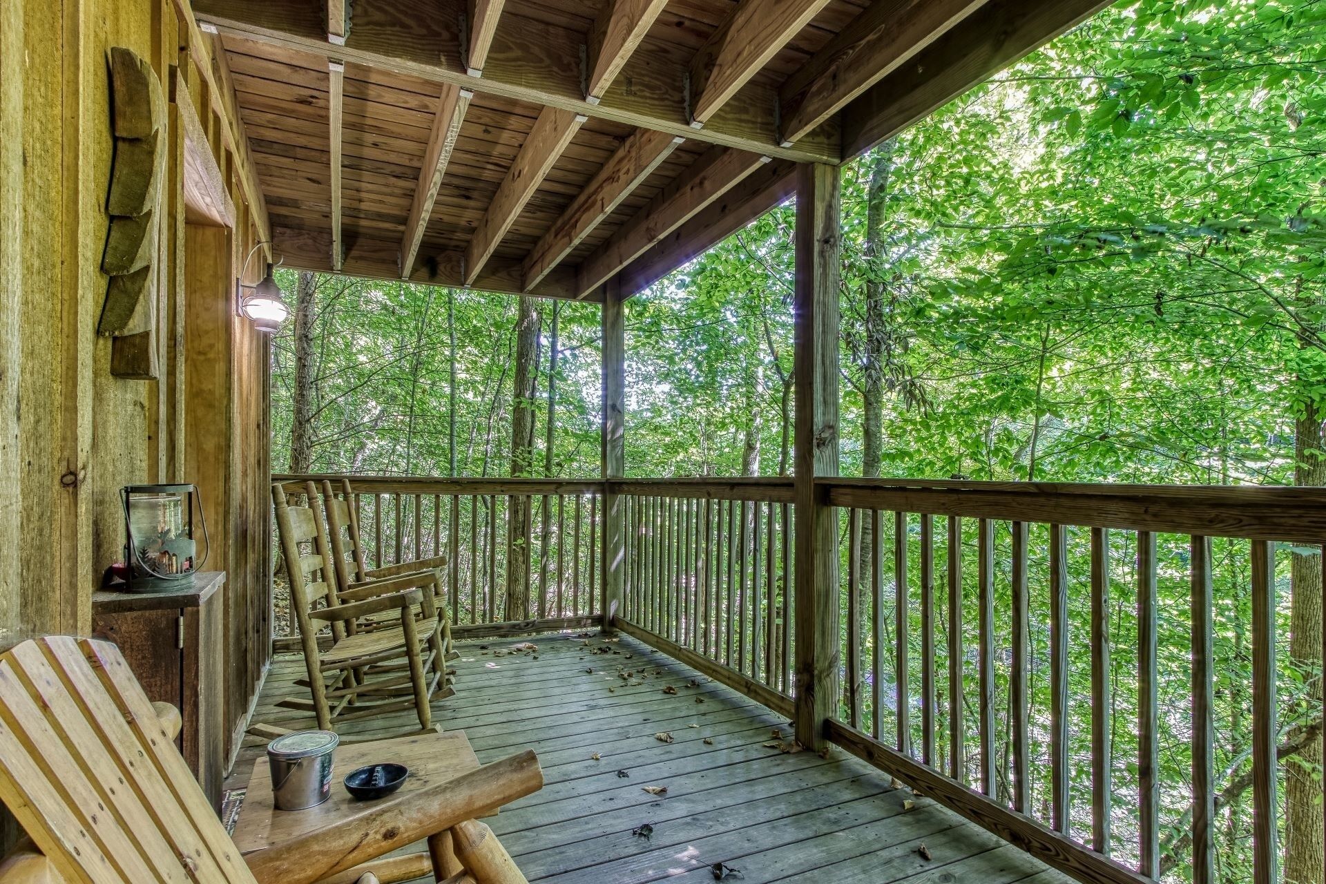Une terrasse en bois avec une rambarde, un banc et une table sur laquelle se trouvent un seau et un saladier.