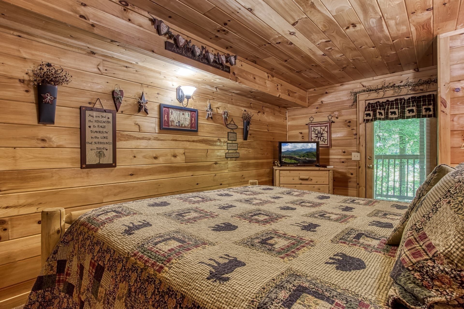 A cozy wooden cabin room with a bed, a television, and various wall decorations.