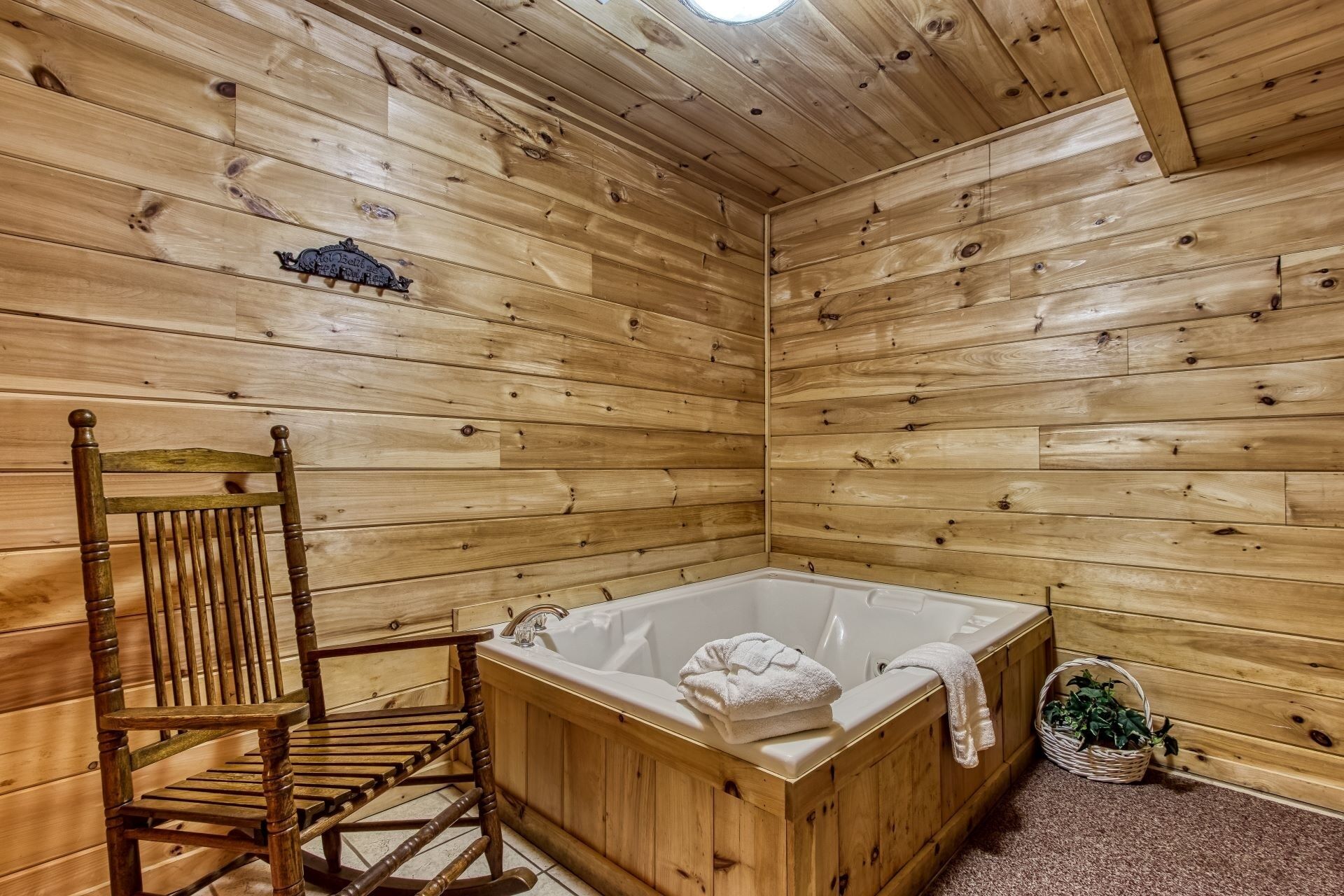 Una cabaña de madera con una silla, una bañera y una planta pequeña.