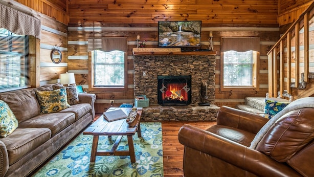 A cozy cabin interior with a stone fireplace, leather furniture, and wooden walls. - Er17 - The Perfect Getaway Great Location - Close To Town! 1 Bedroom Cabin by RedAwning (Pigeon Forge)