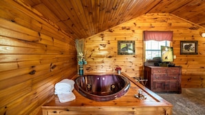 A wooden cabin bathroom with a wooden bathtub, a vanity with a mirror, and framed pictures on the wall. - Er17 - The Perfect Getaway Great Location - Close To Town! 1 Bedroom Cabin by RedAwning (Pigeon Forge)
