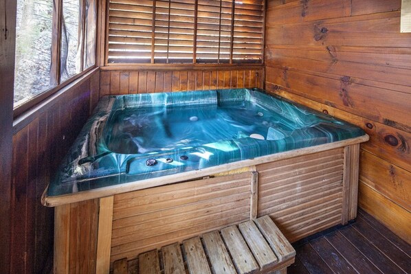 Una cabaña de madera con un jacuzzi con paredes de vidrio.