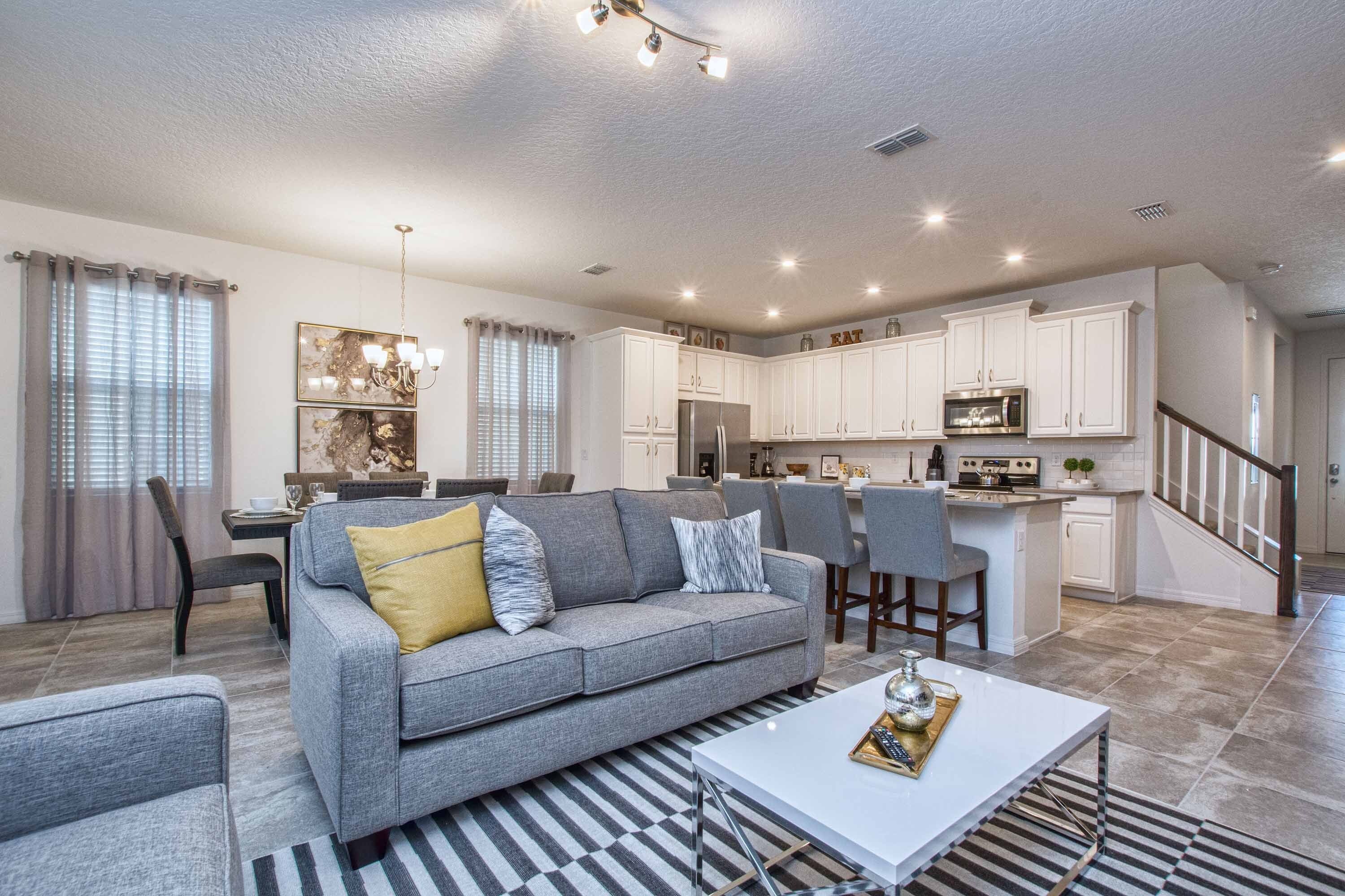A modern living room with a grey sofa, a coffee table, and a striped rug.