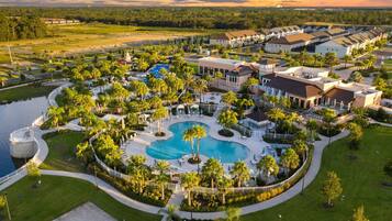 Resort com piscina central, vários edifícios e vegetação ao redor.