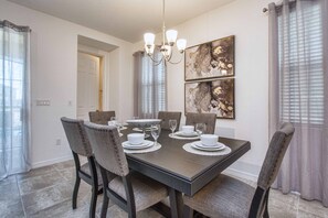 A dining room with a dark wooden table set for four, surrounded by upholstered chairs.