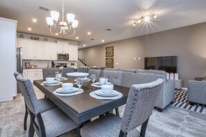 A modern kitchen with white cabinets, a microwave, and a dining area with a dark table set for six.