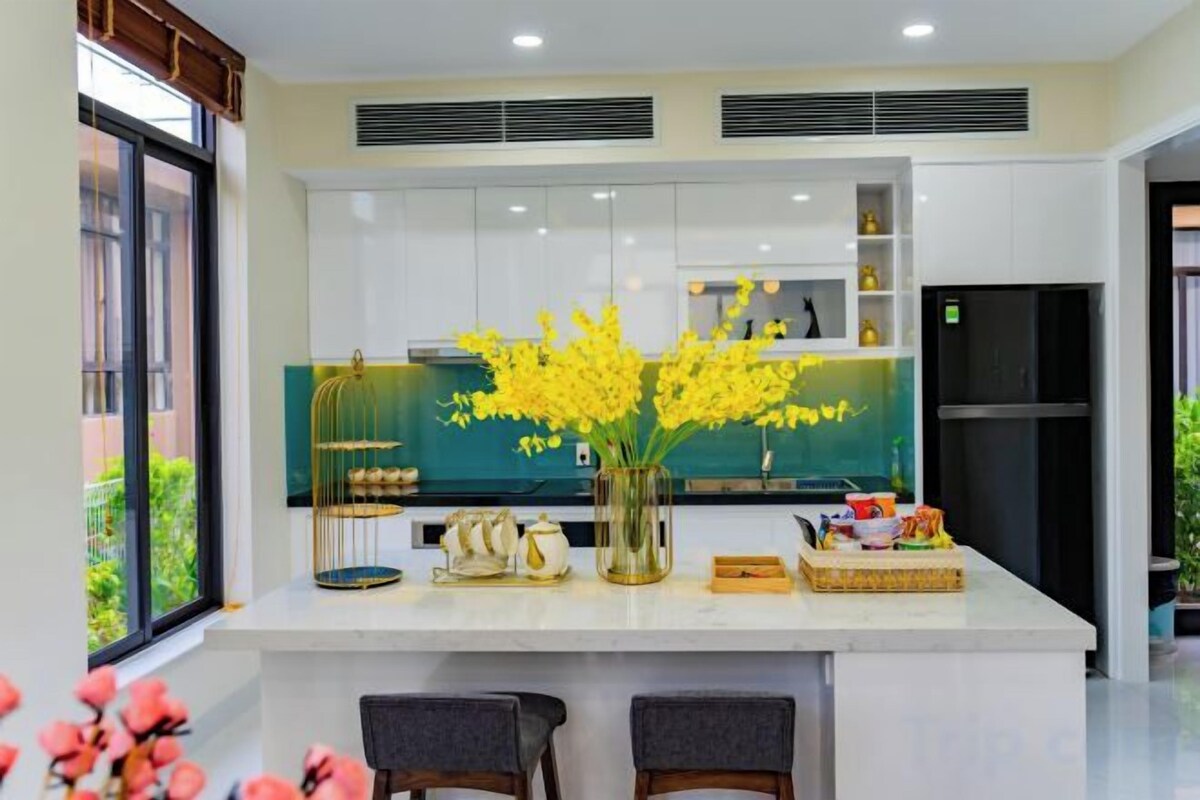 Una cocina moderna con una isla central, armarios blancos y un ventanal que proporciona luz natural.